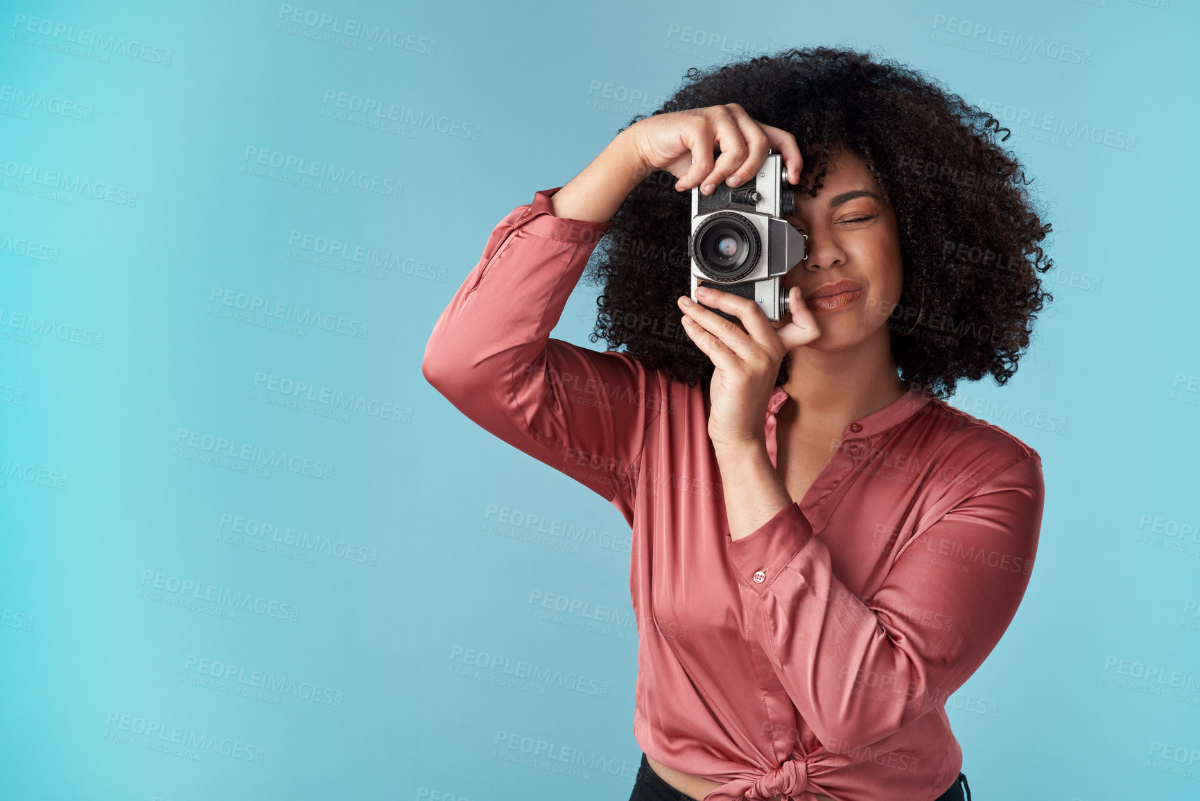 Buy stock photo Studio shot of a young woman using a camera against a blue background