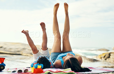 Buy stock photo Shot of a mother and her son playing putting their legs in the air at the beach