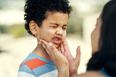 Buy stock photo Shot of a mother applying sunscreen to her son at the beach