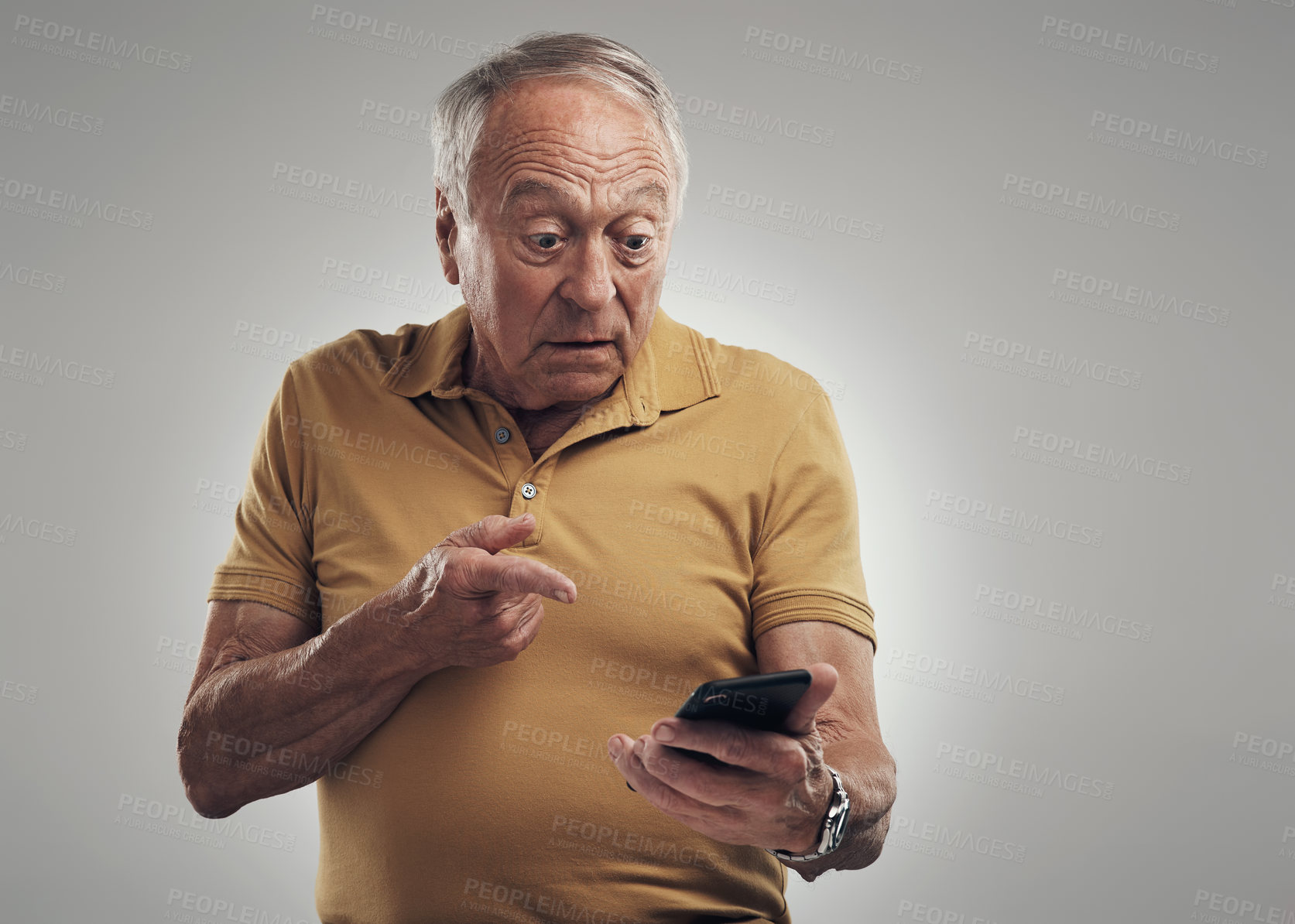 Buy stock photo Studio shot of an elderly man using his cellphone against a grey background