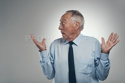 Buy stock photo Shot of a senior businessman standing alone against a grey background and looking surprised