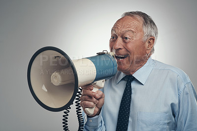Buy stock photo Shot of a senior businessman standing alone against a grey background in the studio and using a megaphone
