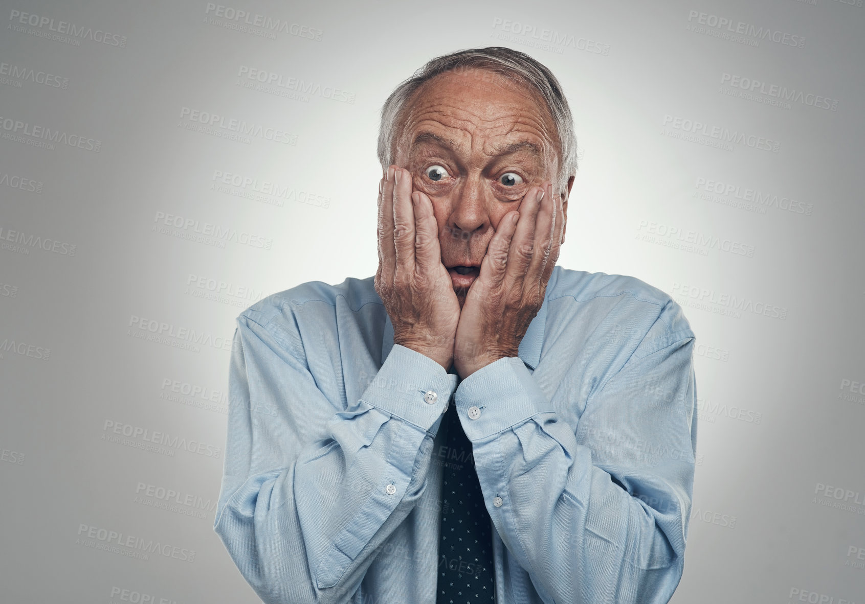 Buy stock photo Shot of a senior businessman standing against a grey studio background with his head in his hands and looking scared