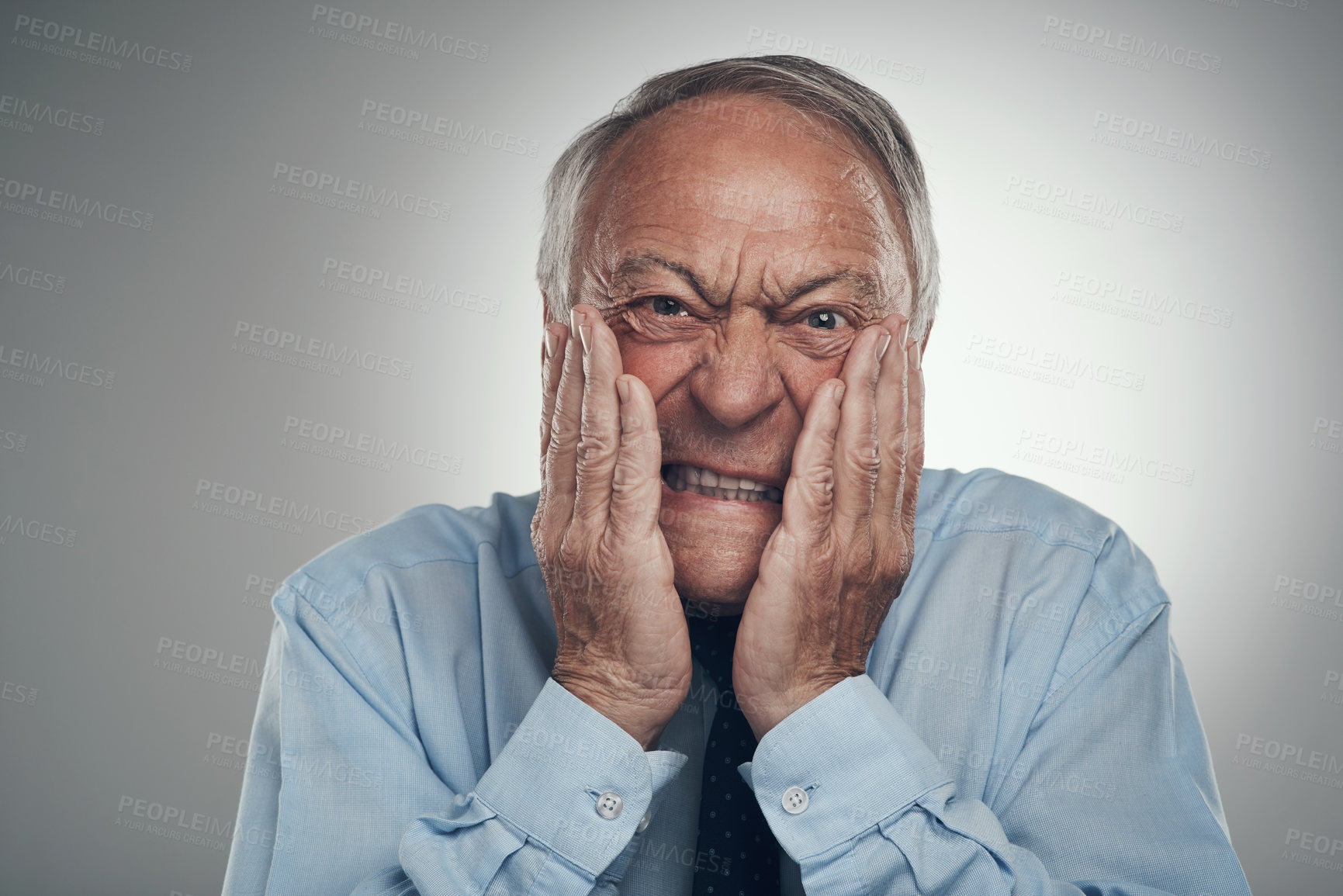 Buy stock photo Shot of a senior businessman standing against a grey studio background with his face in his hands and looking concerned