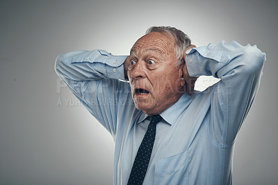 Buy stock photo Shot of a senior businessman standing against a grey studio background with his head in his hands and looking shocked