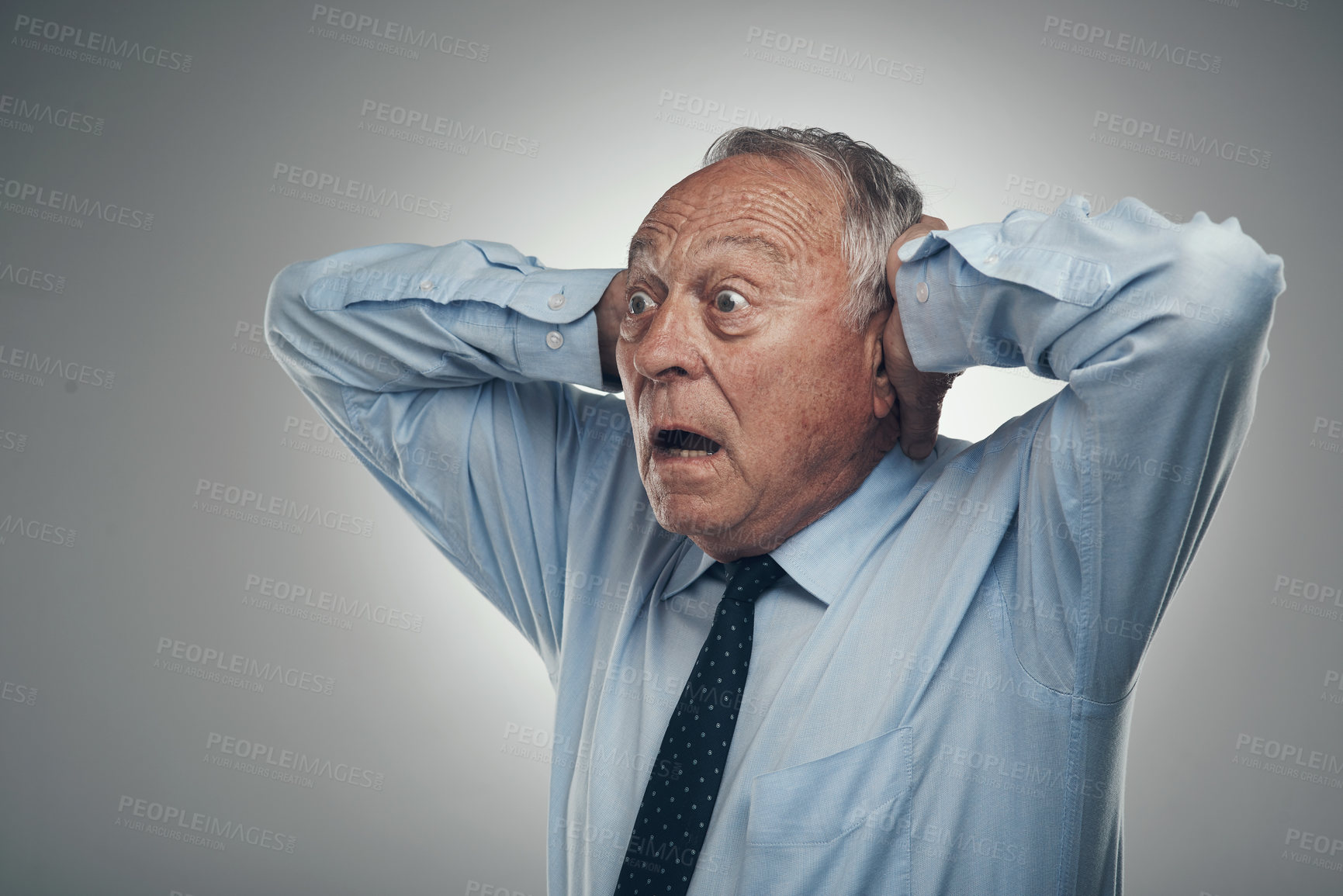 Buy stock photo Shot of a senior businessman standing against a grey studio background with his head in his hands and looking shocked