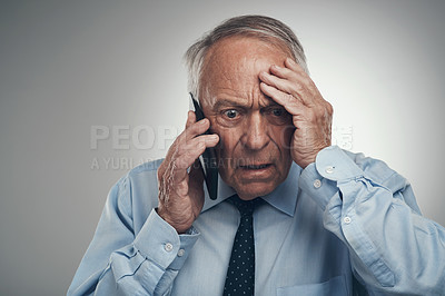 Buy stock photo Shot of a senior businessman standing alone against a grey studio background and looking stressed while using his cellphone