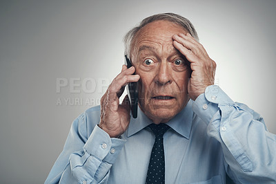 Buy stock photo Shot of a senior businessman standing alone against a grey studio background and looking shocked while using his cellphone