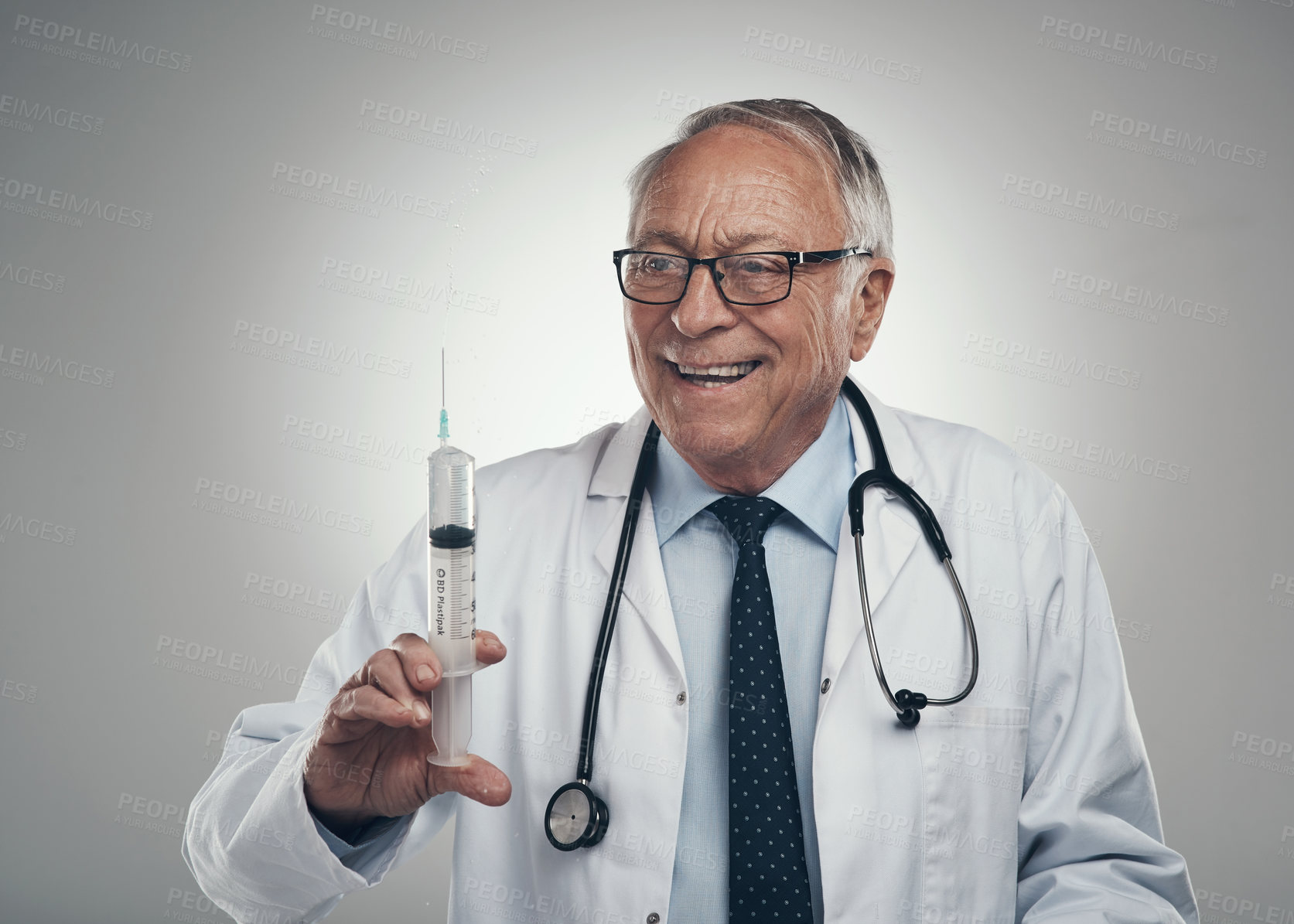 Buy stock photo Shot of an elderly male doctor holding a syringe for injection in a studio against a grey background