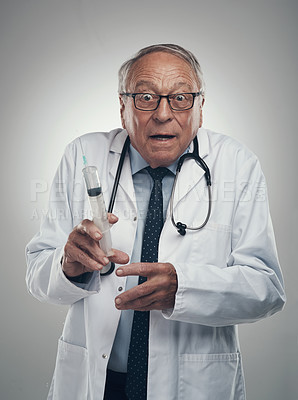 Buy stock photo Shot of an elderly male doctor holding a syringe for injection in a studio against a grey background