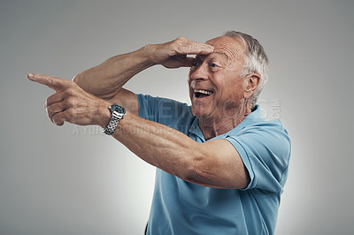 Buy stock photo Shot of an older man with his hand covering his face looking off into the distance in a studio against a grey background