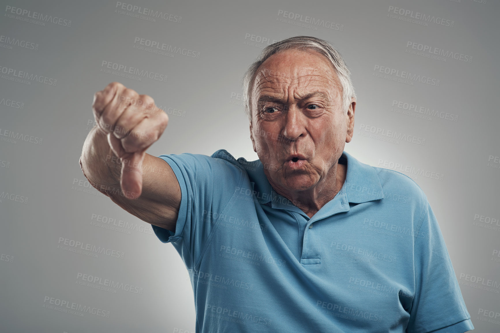 Buy stock photo Shot of a unhappy older man giving the thumbs down in a studio against a grey background