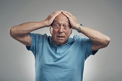 Buy stock photo Shot of an elderly man clasping his hands to his head in a studio against a grey background