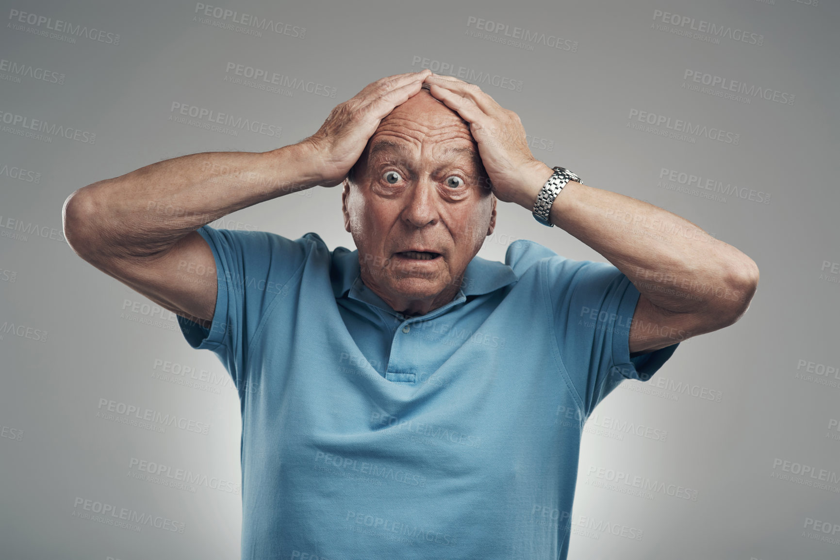 Buy stock photo Shot of an elderly man clasping his hands to his head in a studio against a grey background