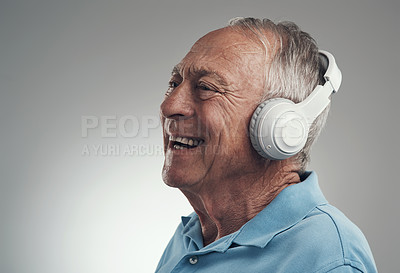 Buy stock photo Shot of an elderly male wearing headphones and listening to music in a studio against a grey background