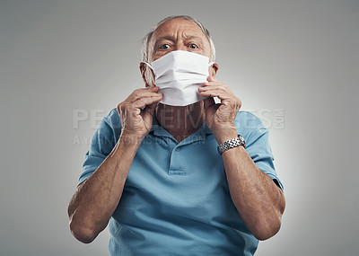 Buy stock photo Shot of an older man wearing a protective face mask in a studio against a grey background