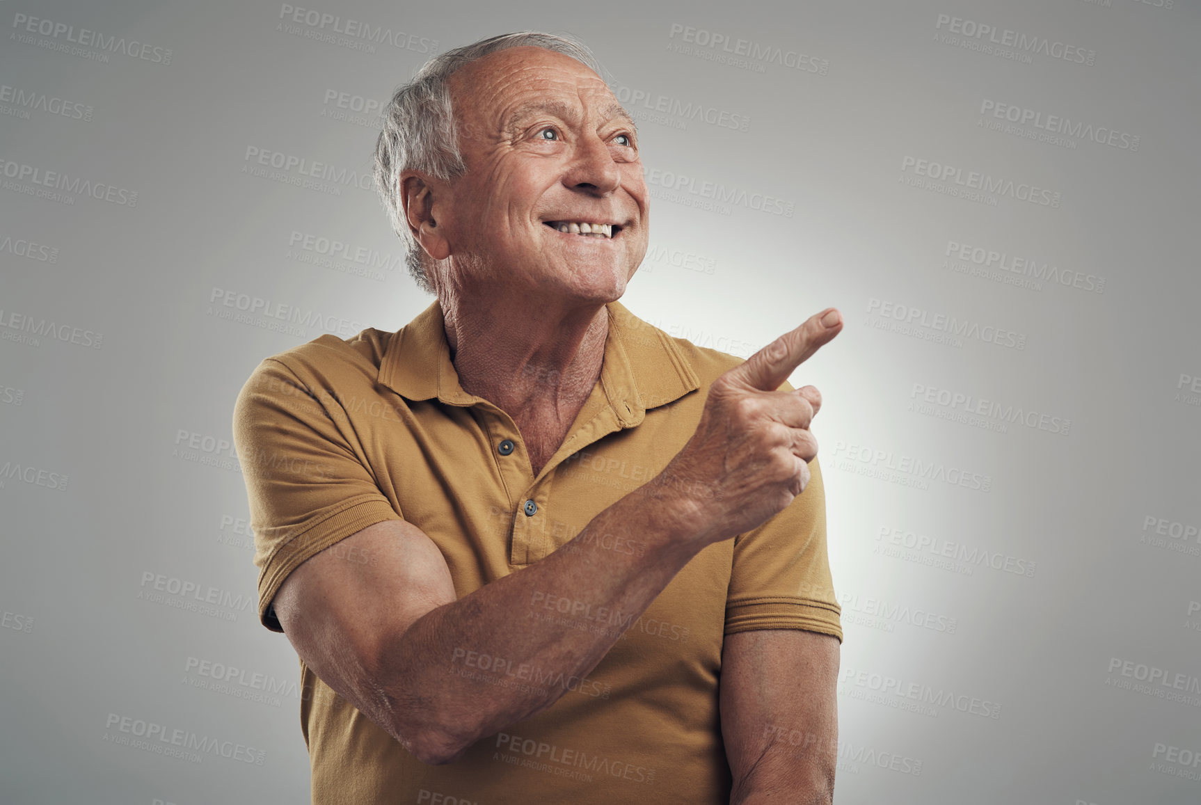 Buy stock photo Studio shot of an elderly man pointing in at something and smiling against a grey background