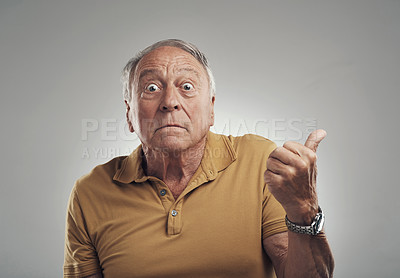 Buy stock photo Studio shot of an elderly man pointing in at something against a grey background