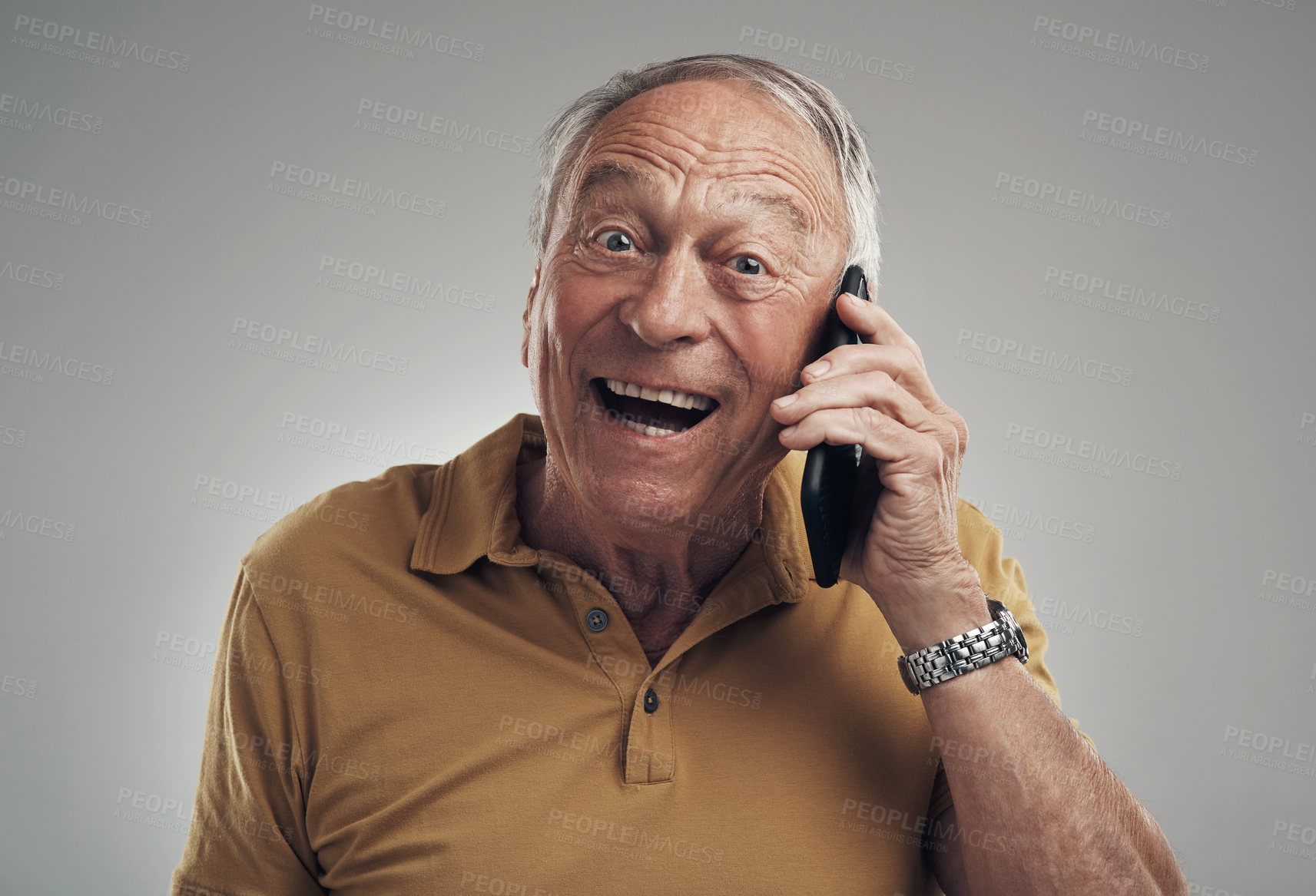 Buy stock photo Studio shot of an elderly man using his cellphone against a grey background