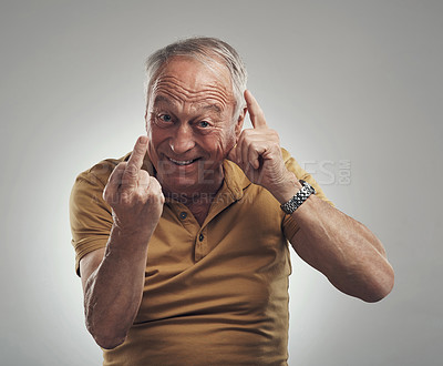 Buy stock photo Studio shot of an elderly man showing his middle finger against a grey background