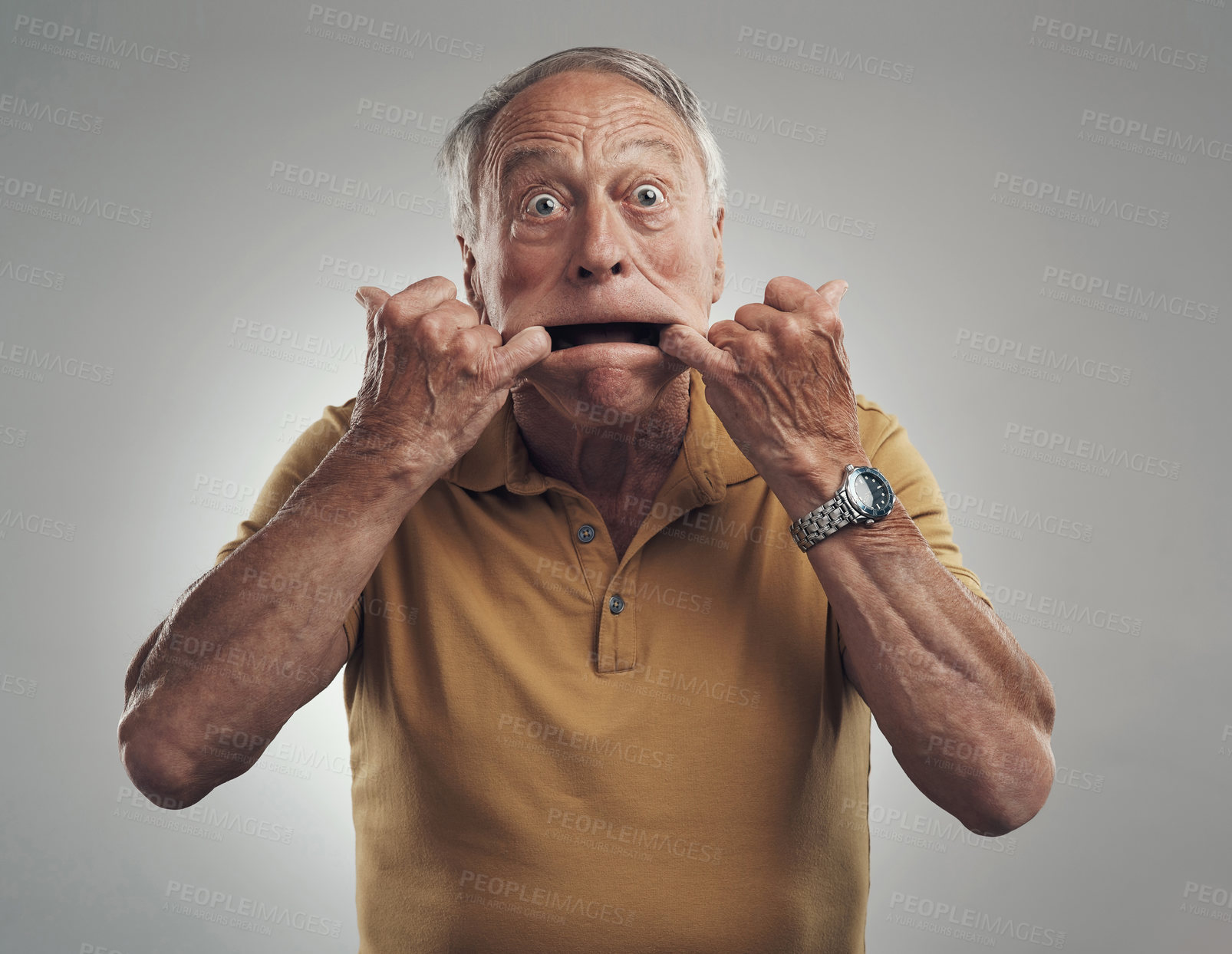 Buy stock photo Studio shot of an elderly man making a funny face against a grey background