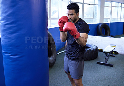 Buy stock photo Fitness, boxing and man in gym with punching bag for exercise, workout or training for healthy body wellness. Sport, gloves and serious athlete in club for fight practice, competition or self defense