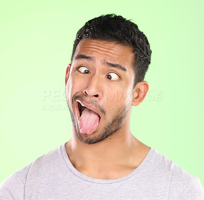 Buy stock photo Man, crosses eyes and tongue in studio, silly and goofy comic or funny face on green background. Male person, mockup space and emoji for joke or comedy humor, student and quirky or crazy character