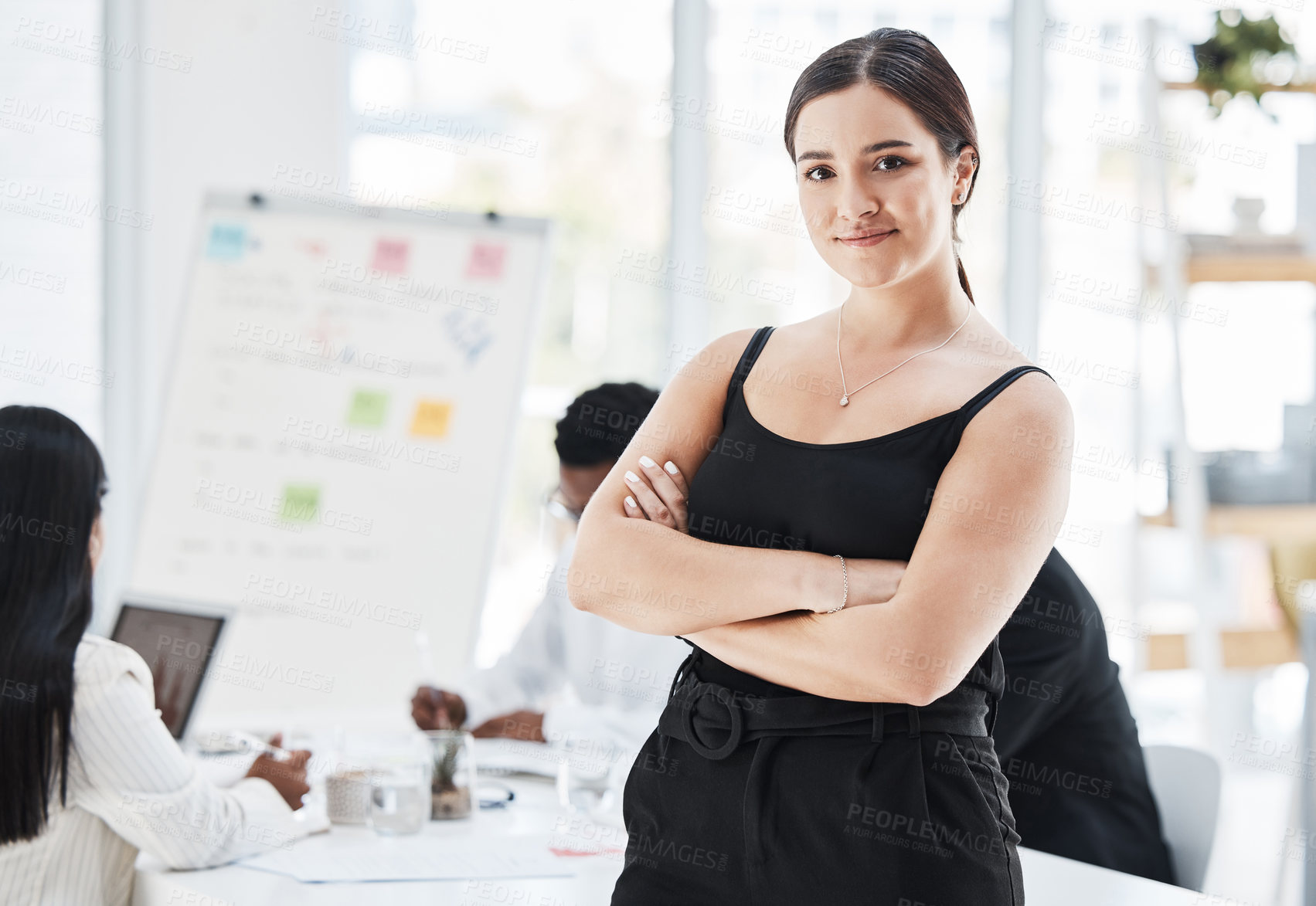 Buy stock photo Portrait of a young businesswoman standing in an office with her colleagues in the background