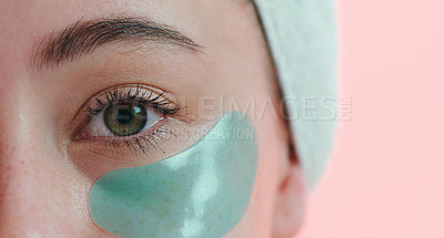 Buy stock photo Cropped studio portrait of a young woman with an eye treatment on her face against a pink background