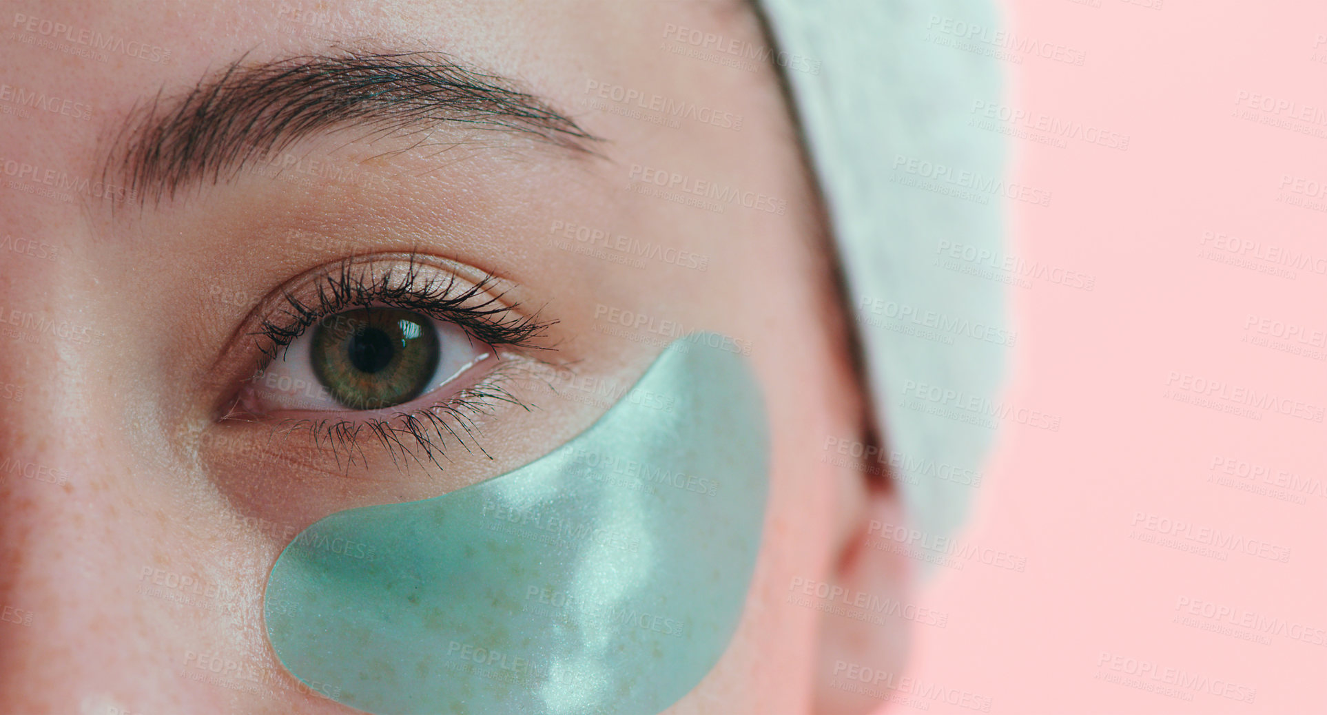 Buy stock photo Cropped studio portrait of a young woman with an eye treatment on her face against a pink background