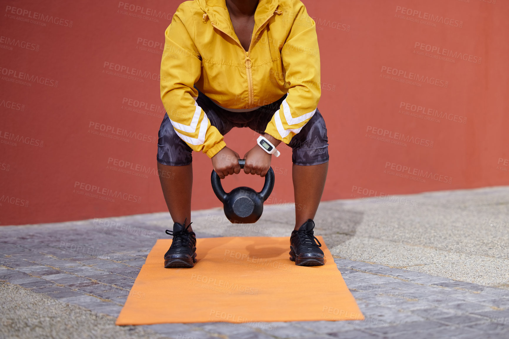 Buy stock photo Cropped shot of a woman on a gym mat using a kettlebell against an urban background
