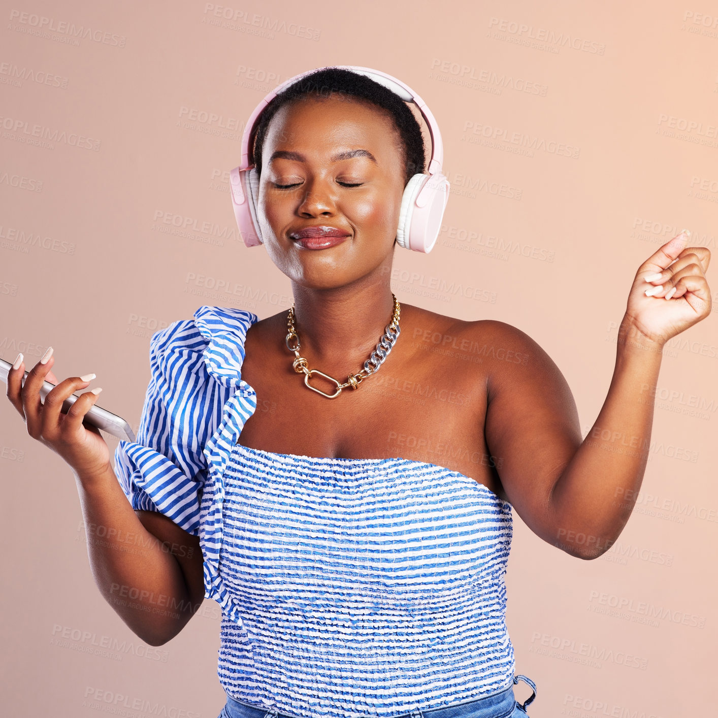 Buy stock photo Studio shot of a young woman using a smartphone and headphones against a pink background