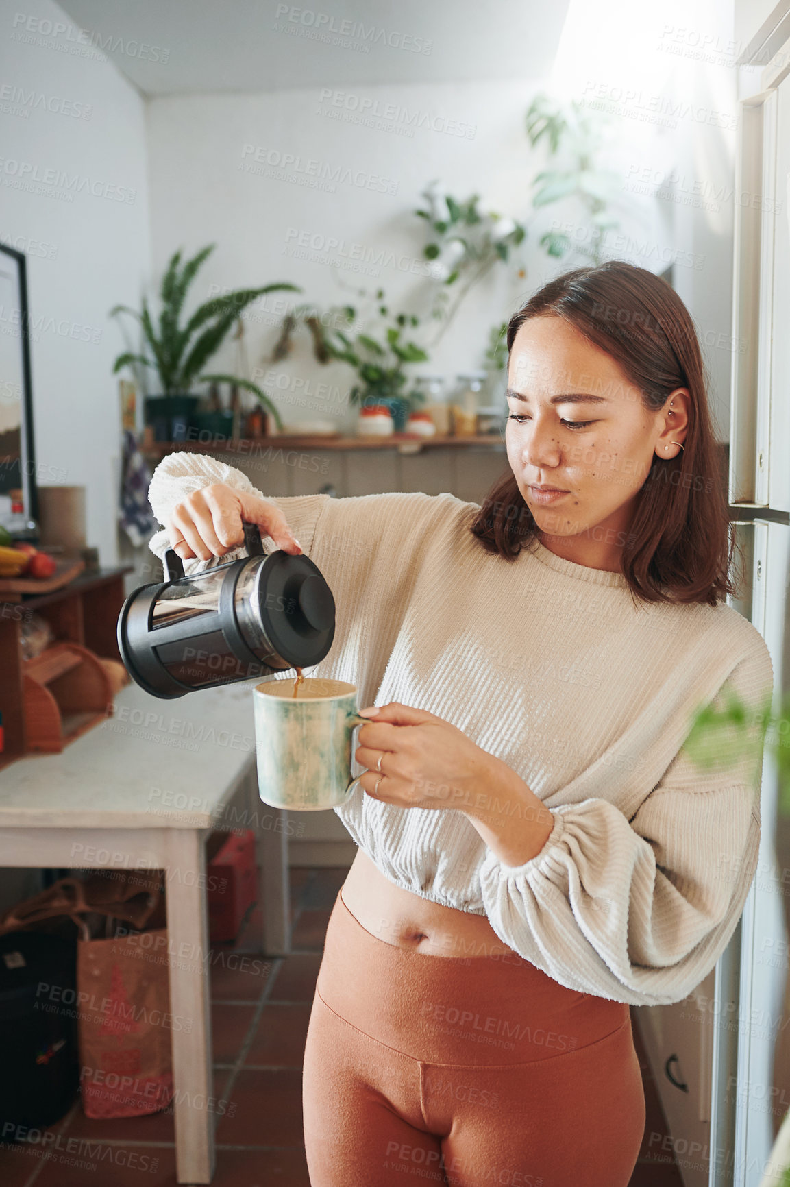 Buy stock photo Shot of a young woman pouring herself a cup of coffee