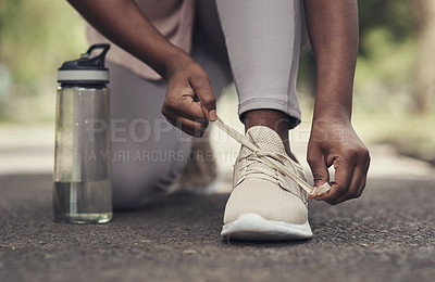 Buy stock photo Shot of a woman tying her shoes before working out