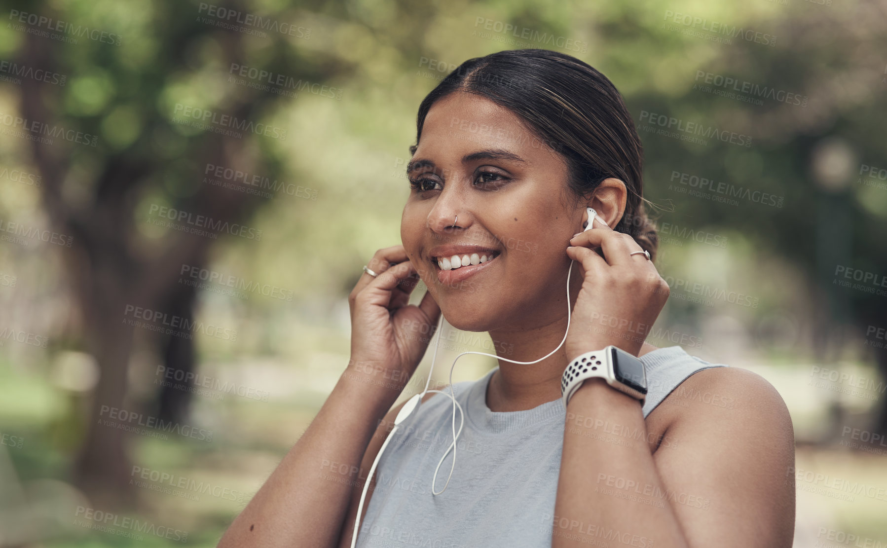 Buy stock photo Shot of a young woman using her earphone to listen to music during a workout