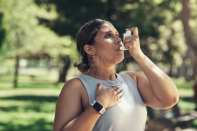 Buy stock photo Shot of a young woman taking a break during a workout to use her asthma pump