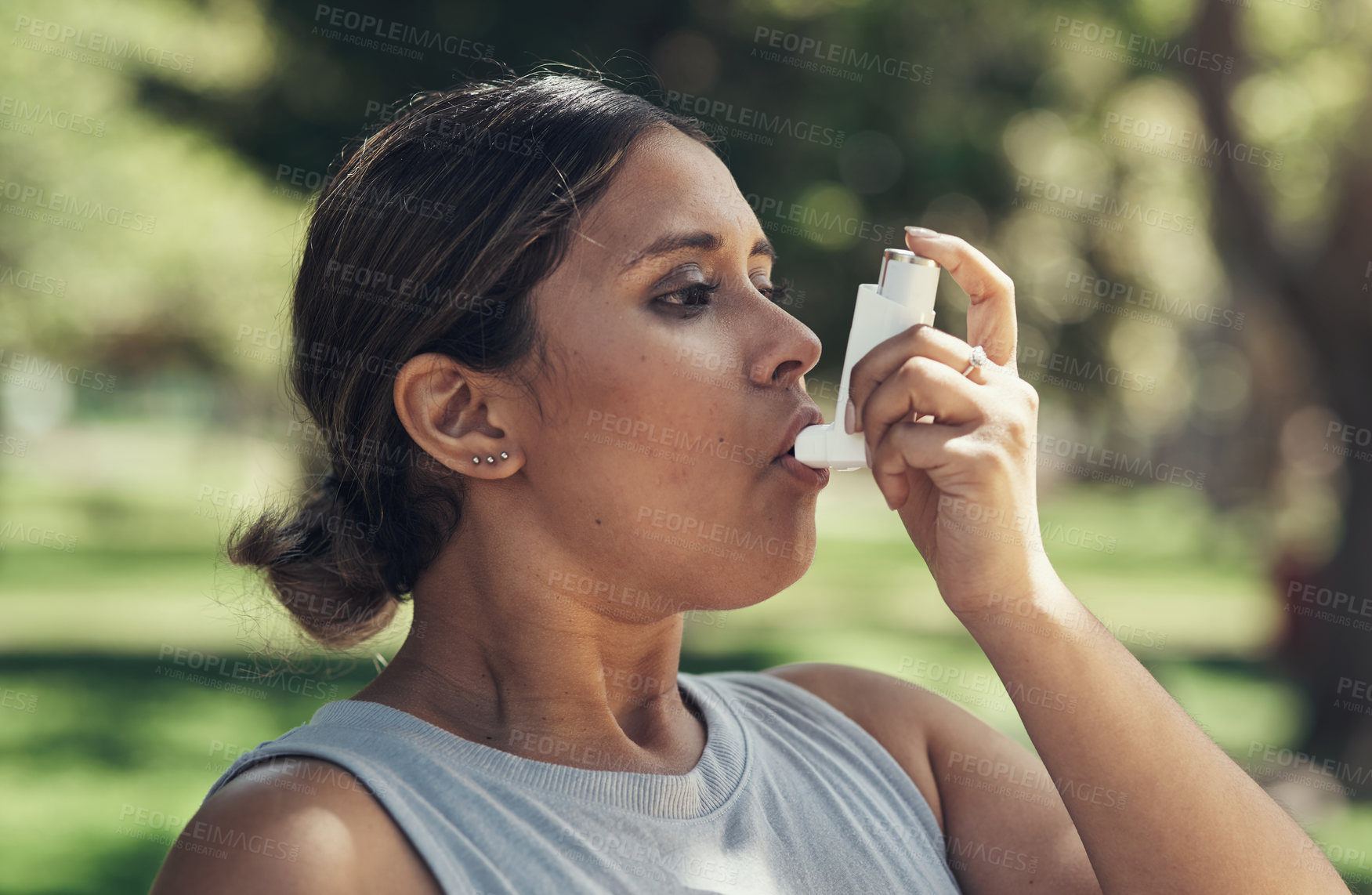 Buy stock photo Shot of a young woman taking a break during a workout to use her asthma pump