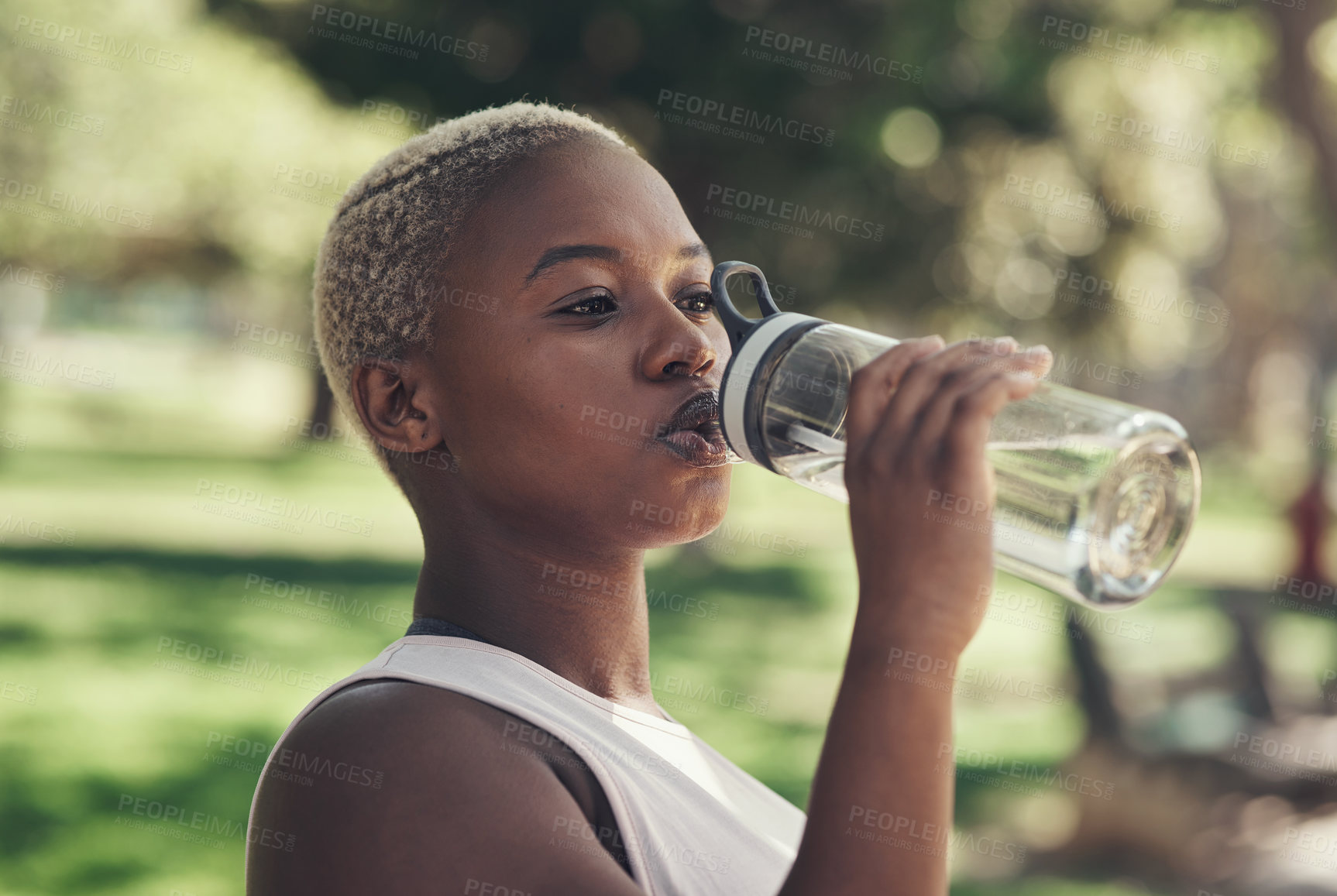 Buy stock photo Shot of a young woman taking a break during a workout to drink water