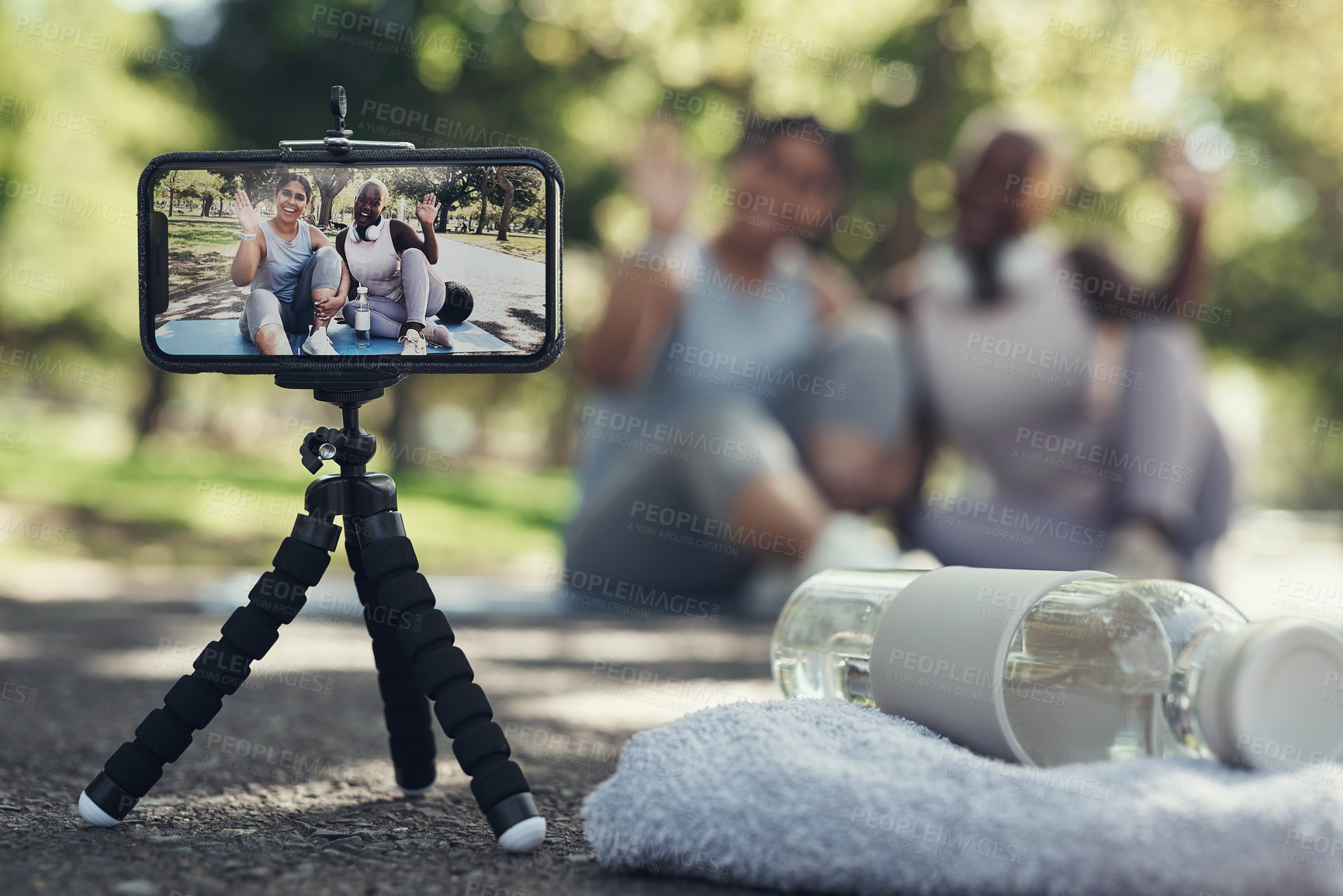 Buy stock photo Shot of two female friends taking a break to livestream their workout