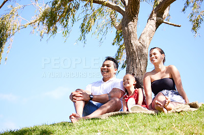 Buy stock photo Parents, girl and happy at picnic in park to relax by trees for holiday, bonding and love in nature. Father, mother and daughter on lawn, grass and outdoor for sunshine with care, smile and family