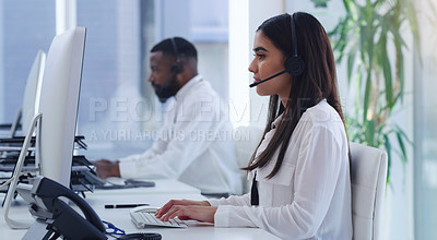 Buy stock photo Shot of a young businesswoman working on a computer in a call centre with a colleague in the background