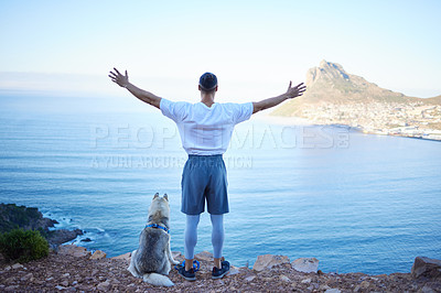 Buy stock photo Rearview shot of an unrecognizable young man and his pet husky taking in the views during their early morning hike in the mountains