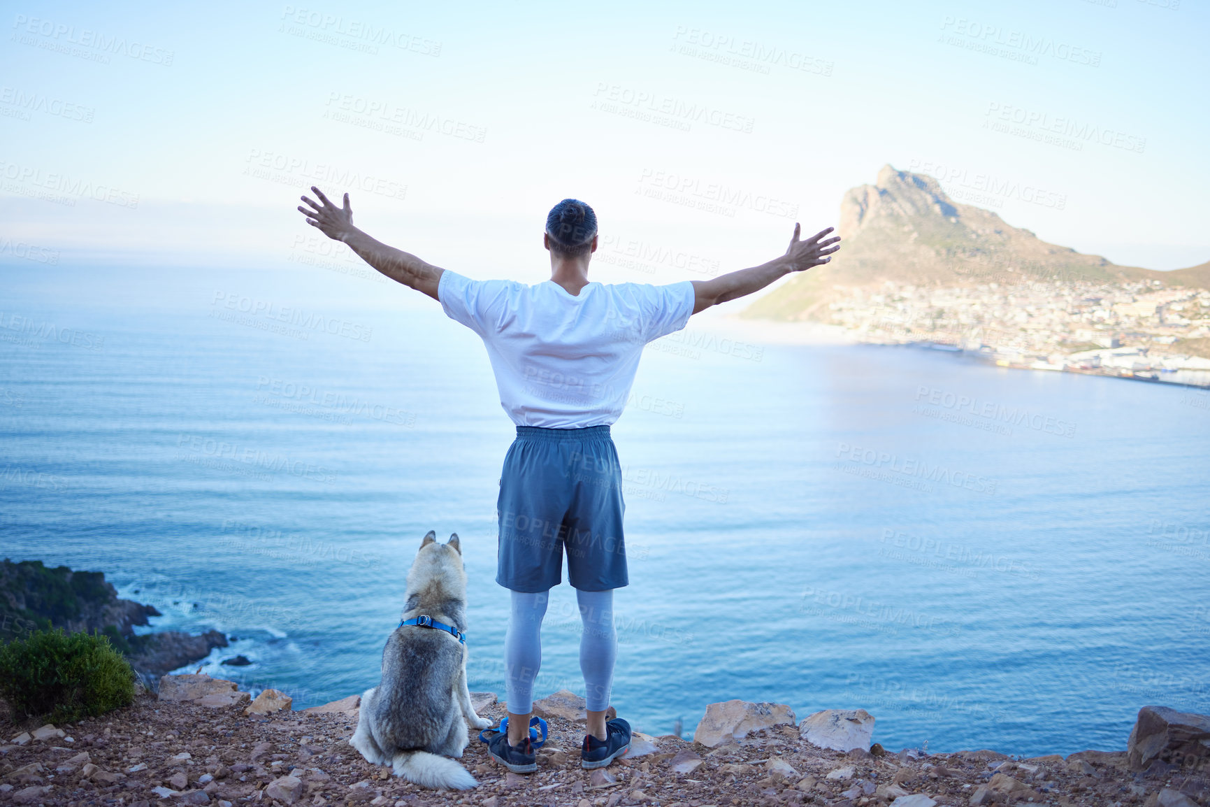 Buy stock photo Rearview shot of an unrecognizable young man and his pet husky taking in the views during their early morning hike in the mountains