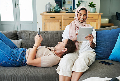 Buy stock photo Muslim, woman and friends on couch, technology and relax, game and app in phone, tablet and home. House, lounge and female person with hijab, digital and mobile for texting, communication and website
