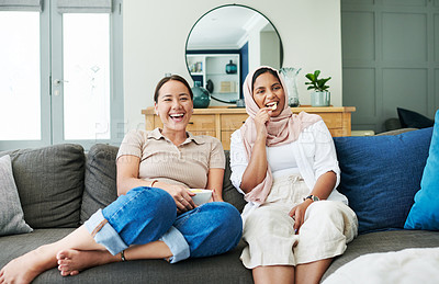 Buy stock photo Shot of two women sitting on the sofa at home together and bonding while watching a movie and eating snacks