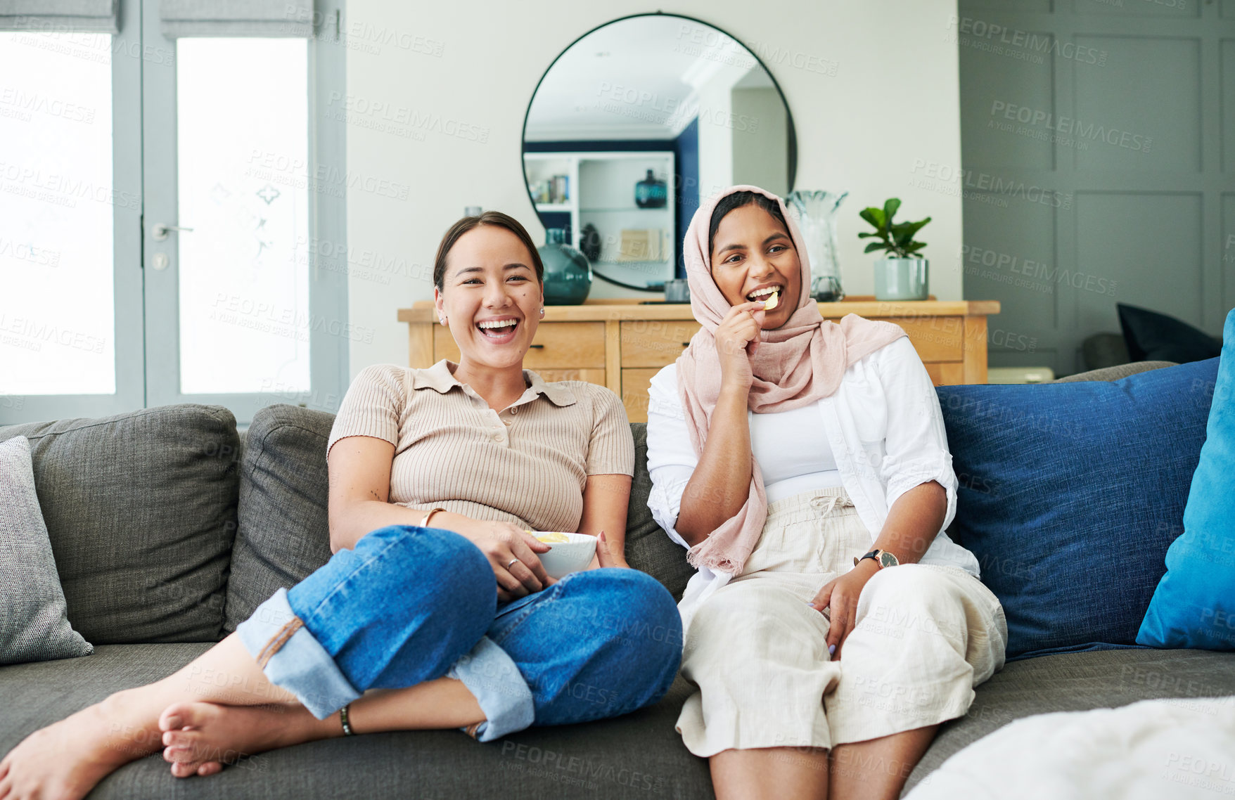 Buy stock photo Women friends and eating on sofa with smiling for happy in house for relax with snack. Female people, couch and living room and laugh with islam for diversity with asian with streaming in apartment