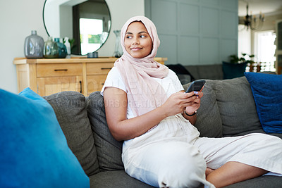 Buy stock photo Muslim, woman and sofa on cellphone with smile in living room for break, leisure and network or satisfied. Female person, lounge and holiday with day off to relax, chill and calm on couch at home