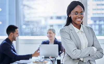 Buy stock photo Portrait of a confident young businesswoman standing in an office with her colleagues in the background