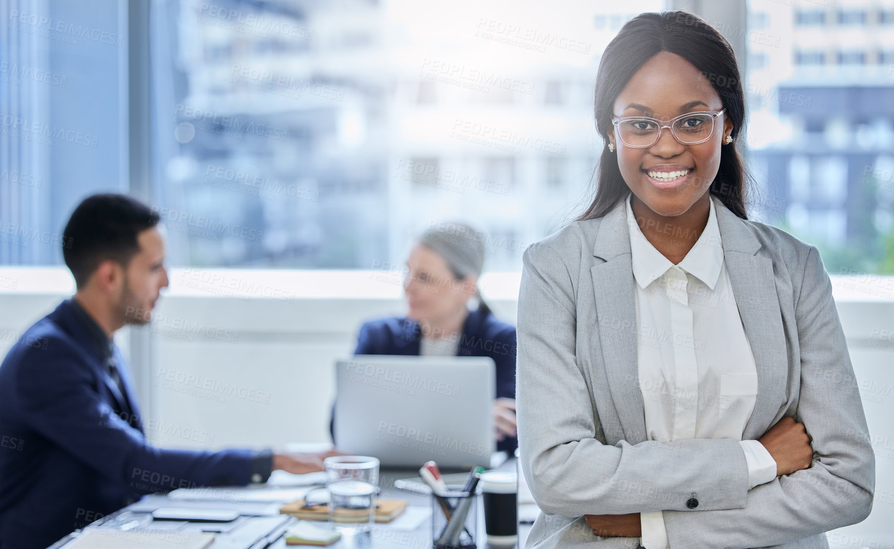 Buy stock photo Portrait of a confident young businesswoman standing in an office with her colleagues in the background