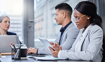 Buy stock photo Shot of a young businesswoman using a digital tablet during a meeting with her colleagues in a boardroom